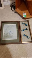 Framed original dragonfly painting by Gisela Downey with adjacent glass frame holding three blue dragonflies.