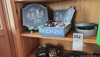 Wooden folk art items including rectangular box, wooden board, and oval box, displayed on a shelf with other items