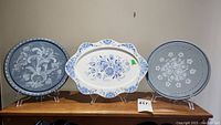 Three handpainted Gisela plates displayed on stands showing floral designs