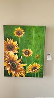 Photo of full sunflower painting against wall.