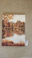 Full front view of signed landscape painting on canvas depicting autumn trees and water reflection, showing overall condition and color detail.