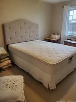 Full view of queen size bed with mattress, box spring skirt, and padded headboard in a bedroom.