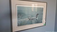 Full front view of framed lithograph print showing two loons on water
