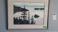 Framed watercolor landscape painting of mountain and water scene.