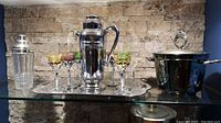 Wide shot showing full barware set including tray, shaker, colored stem glasses, ice bucket, and decanter on shelf.