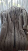 Full view of the long fur coat draped on a chair showing the overall color and texture