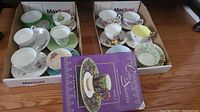 Overview of twelve assorted cups and saucers in two boxes along with Collectible Cups & Saucers Book II