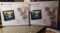 Two boxed Fidelity Electronics digital picture frames shown side-by-side on countertop with packaging visible including product images and labels.