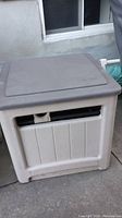 Front view of the closed Suncast hose reel box outdoors, showing the vent openings and textured exterior.