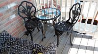 Full view of black cast iron bistro table and two chairs on porch