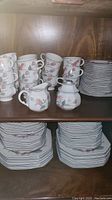 Overall set on wooden hutch shelf: stacks of cups, bowls and dinner plates