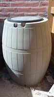 Rain barrel front and side view showing overall shape, lid, and dent.