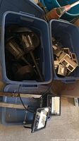 Blue storage bin filled with multiple solar fence post topper yard lights and some smaller edge lighting fixtures.