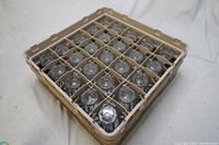 Top view of 20 heavy duty durable water glasses neatly organized in a beige plastic wash tray with individual compartments.