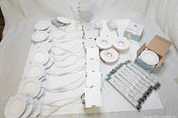 Lot showing multiple round LED dimmable pot lights with wires, LED drivers, and accessories spread out on a white surface.