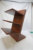 Main view of the wooden shoe stand showing the three slanted shelves and overall structure.