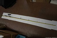 Full length view of the yellow Mitchell fishing rod stretched on a white background showing the eyelets and handle.