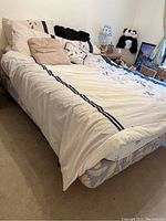 Full view of the queen bed with bed frame, mattress with patterned cover, pillows, and bedding set in a bedroom environment.