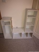 Three white cubby cabinets together with visible scratches and surface wear