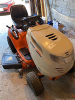 Front/side view of tractor showing orange body, cream hood, black seat and overall condition