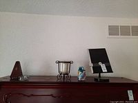 Wooden metronome on left, glass candle holder center with metal curly feet, small decorative jar to right, and Copymate music stand on far right.