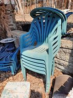 Stack of green plastic outdoor chairs showing front and side profiles