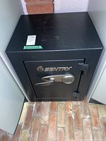 Front view of black Sentry safe inside a cabinet, showing external structure and size.