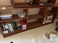 Side and front view of teak bookcase bottom section with three shelves showing various items placed but not included.