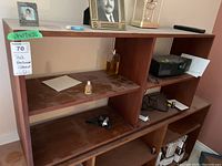 Front view of the teak bookcase showing two fixed shelves and dusty surfaces with some small items placed on shelves.