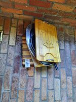 Lot showing all items stacked: two wooden cutting boards with carved grooves and metal handles, black metal steak board, round metal tray.
