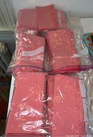 Six dozen pink tone April Cornell cotton cloth napkins, folded and packed in plastic bags.