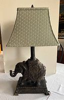 Front view of the lamp showing the full fabric shade and elephant figurine base on a rectangular platform.
