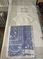 Large embroidered rectangular tablecloth with lace bread basket napkins and packaged lace tablecloth placed on top