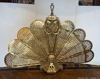 Full front view of brass fan screen showing fan-shaped panels and finial