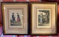 Both framed lithographs side by side on a patterned sofa, showing the vintage prints inside wooden frames with gold trim.