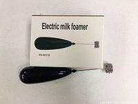 Boxed black electric milk frother model KN-8221B showing front packaging with device image and text.
