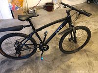 Full left-side view of black Macce mountain bike showing frame, saddle, fenders, wheels and handlebars