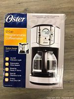 Photo of front of the box showing the Oster 12 cup programmable coffee maker with key features listed.