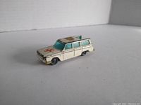 Front and side view showing ambulance emblem, paint wear on roof and body, aqua windows, all wheels attached but front wheel slightly bent.