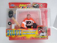 Front view of sealed packaged NHL goalie action figure of John Vanbiesbrouck with goalie net, stick, puck, and helmet included.