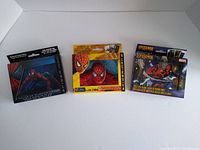 Three sealed Spider-Man playing card collectible tins arranged side by side with original boxes visible.