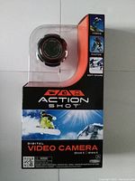 Front view of sealed Action Shot video camera retail package with branding and usage imagery.
