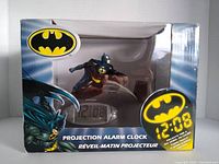 Box front showing Batman figure atop digital projection alarm clock with visible Batman logos and time projection reference