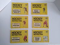 Top view of six vintage hockey instruction booklets from 1972, yellow covers showing titles on skating skills, puck control, shooting, checking, goaltending, team play.