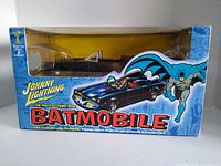 Front of box showing the Johnny Lightning 1960's Batmobile model visible through window with comic-themed graphics.
