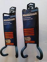 Two Mastercraft bicycle hangers in original packaging showing front and back views.