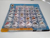 Front view of the full set of 30 NHL mini ceramic mugs in original plastic packaging on blue NHL-themed cardboard backing.