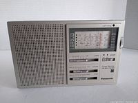 Front view of Panasonic RF-788L portable radio showing speaker grille, tuning window with frequency scale, sliders for setting band, fine tuning, and power controls.