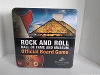 Front view of the Rock and Roll Hall of Fame and Museum Official Board Game metal tin, showing the guitar and museum building artwork on the lid.