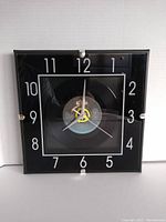 Front view of the framed wall clock featuring The Clash "Rock The Casbah" vinyl record as clock face, with hour numbers arranged around the record.